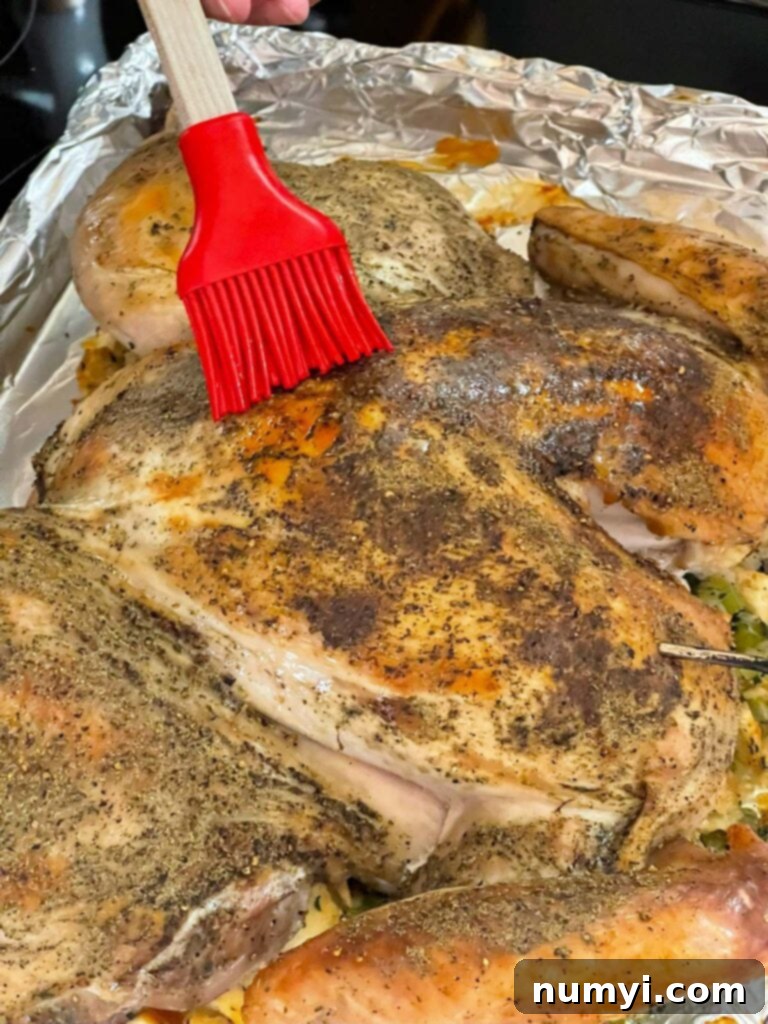 Spatchcocked turkey being basted with melted butter during the roasting process for added moisture and flavor.