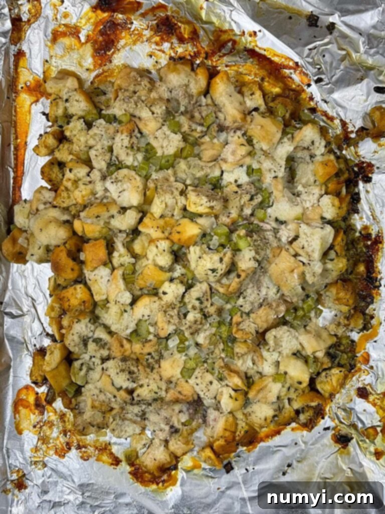 The savory stuffing, now exposed on the baking sheet, ready for its final crisping stage after turkey removal.