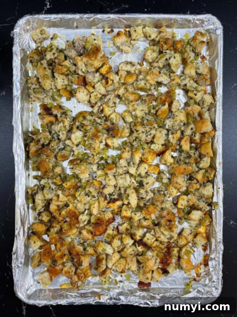 Stuffing generously spread out on a baking sheet to maximize exposed edges for optimal crisping in the oven.