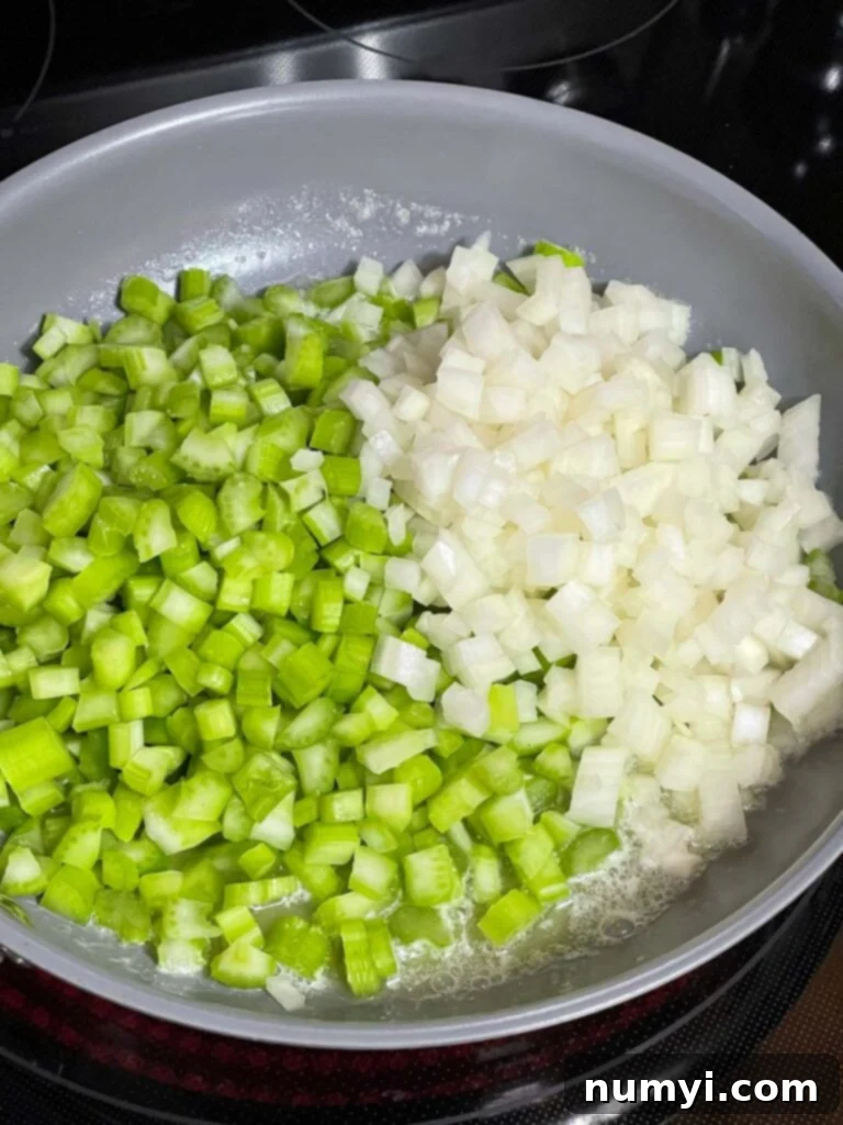 Finely diced onion and celery gently cooking in melted butter in a skillet, softening without browning.